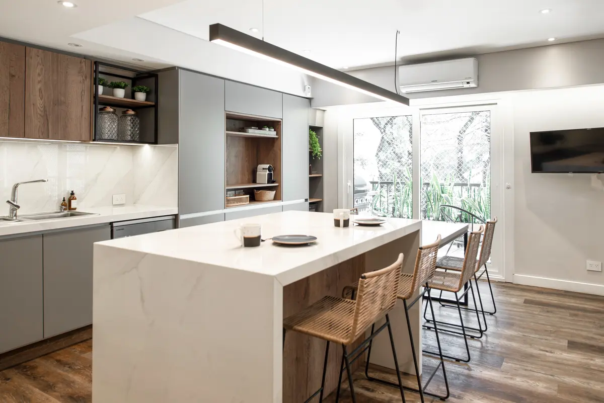 Cocina moderna escandinava con isla grande y sillas de ratán — proyecto Depto Virrey del Pino, por Ayelen Mayer Arquitectura, en Buenos Aires